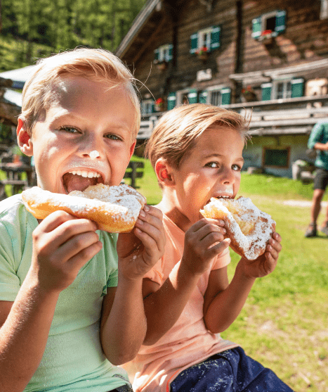 Kinder beim Krapfen essen auf einer Hütte in Flachau © Flachau Tourismus / Markus Berger